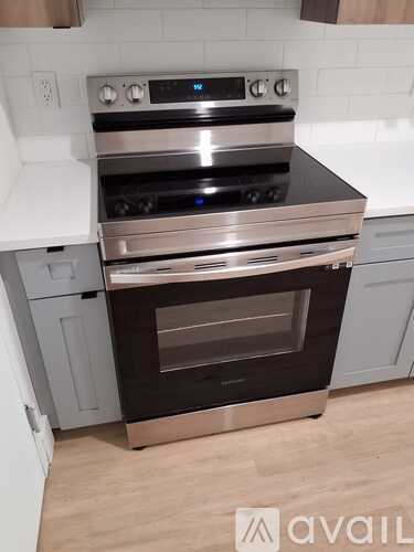 A modern stainless steel oven with a digital display is installed in a kitchen.