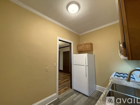 A kitchen area with a white refrigerator and a wooden cabinet.