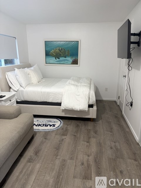 A bedroom with a bed, couch, and a painting of a turtle on the wall.