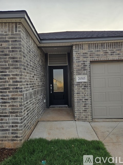 A house with a black door and a garage door is numbered 20505.