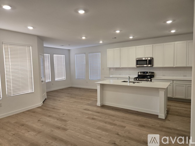 A spacious kitchen with white cabinets and a wooden floor.