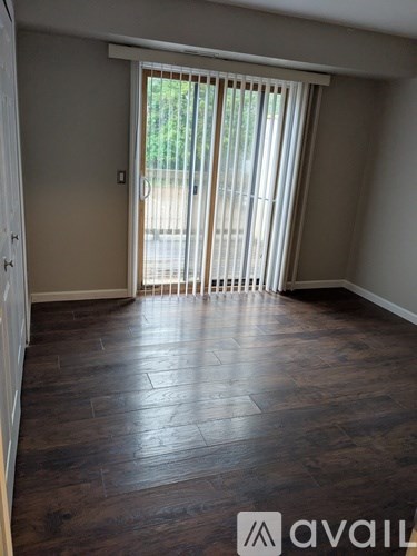 A room with wooden flooring and a sliding door leading outside.