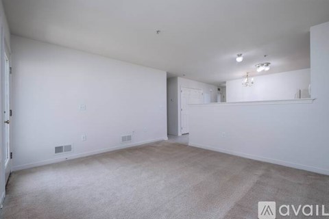 A spacious room with a carpeted floor and a chandelier hanging from the ceiling.