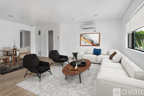A living room with a white couch, a coffee table, and a painting on the wall.