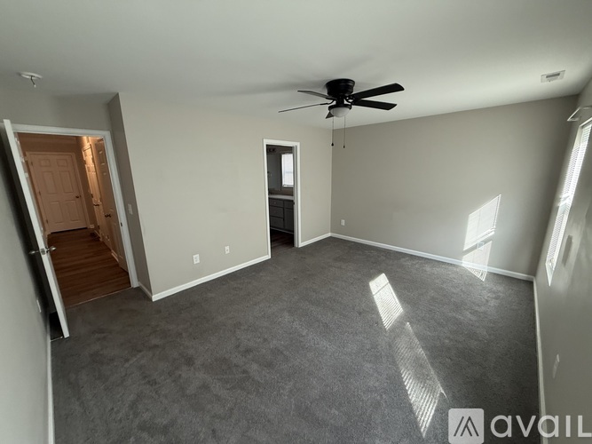 A spacious room with a ceiling fan and a door leading to another room.