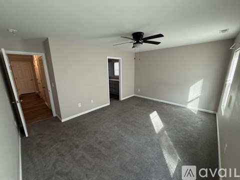 A spacious room with a ceiling fan and a door leading to another room.