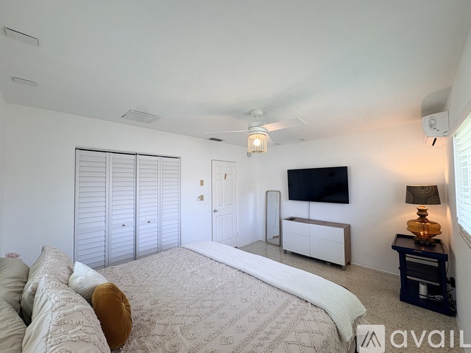 A bedroom with a large bed and a television on the wall.