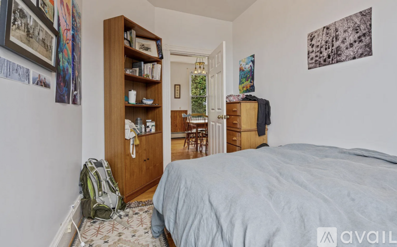 A bedroom with a bed, a bookshelf, and a backpack on the floor.