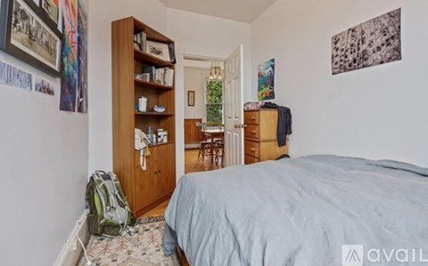 A bedroom with a bed, a bookshelf, and a backpack on the floor.