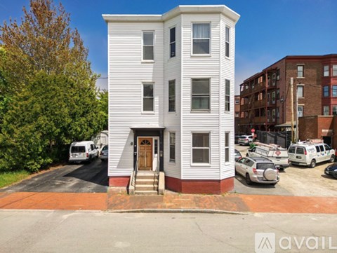 A white two-story building with a brown door and windows.