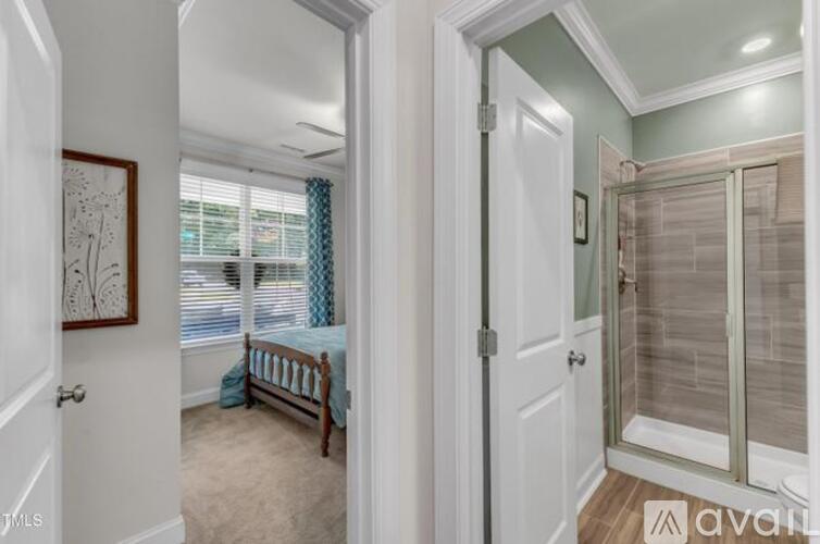 A bedroom with a bed and a glass door leading to a bathroom.