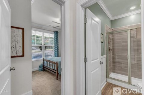 A bedroom with a bed and a glass door leading to a bathroom.