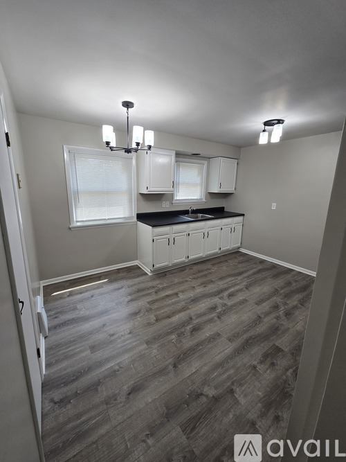 A kitchen with white cabinets and a wooden floor.