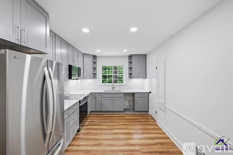 A modern kitchen with wooden floors and stainless steel appliances.