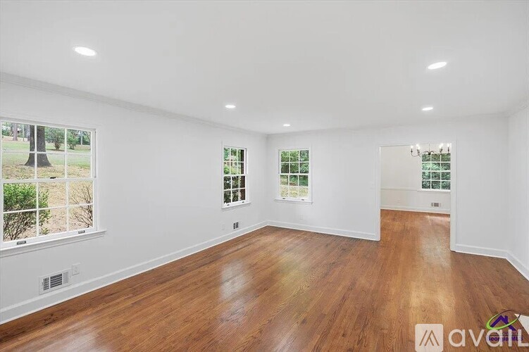 A spacious room with wooden floors and large windows.