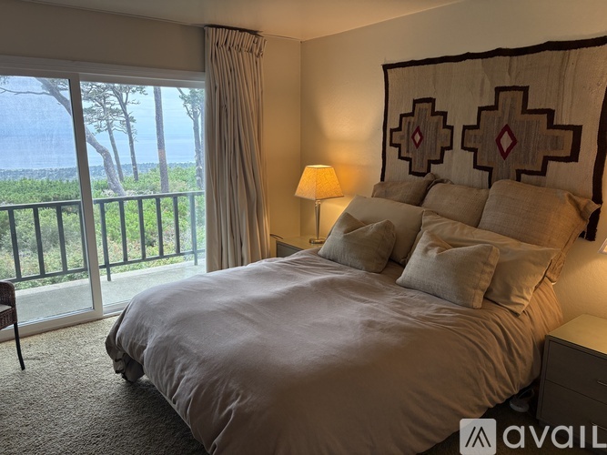 A bedroom with a large bed and a view of the ocean through the sliding glass doors.