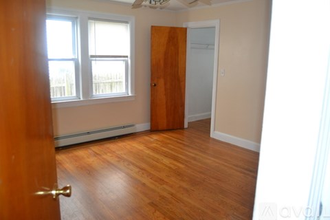 A room with wooden floors and a door leading to another room.