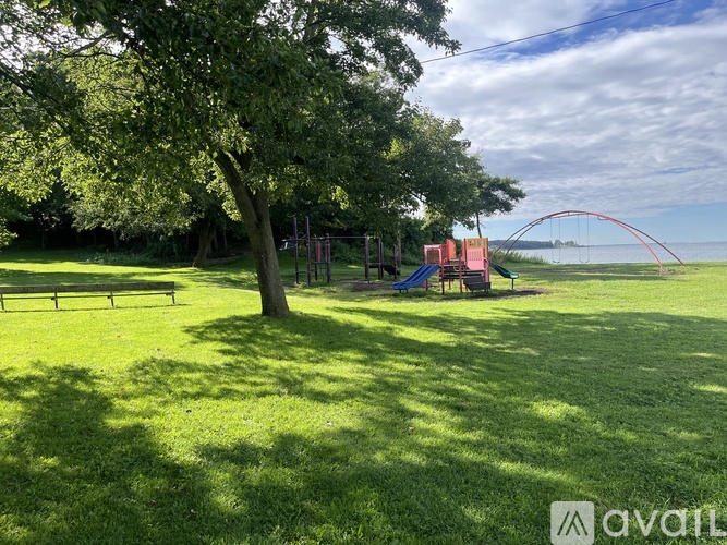A playground with a swing set and a tree in the foreground.