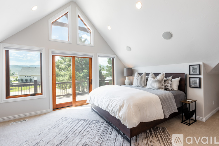 A bedroom with a large bed and a balcony overlooking the ocean.