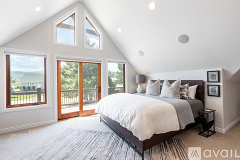 A bedroom with a large bed and a balcony overlooking the ocean.
