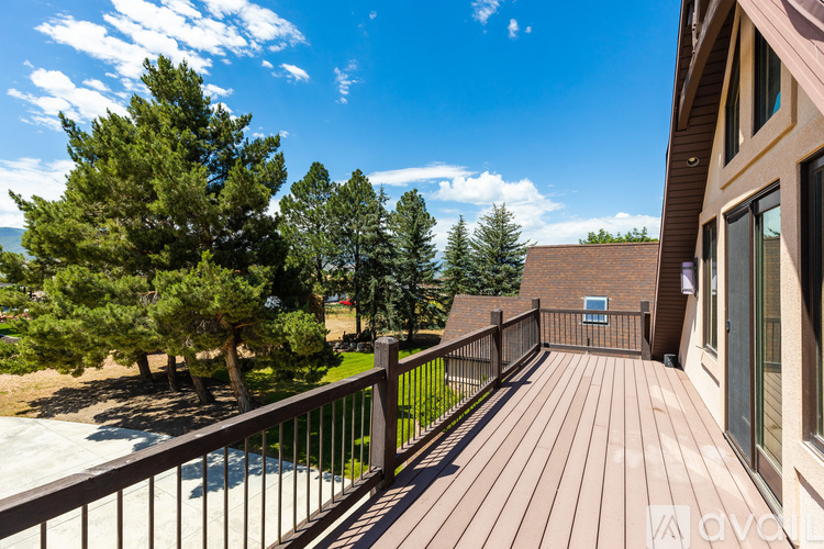 A deck with a railing and a hot tub surrounded by trees.