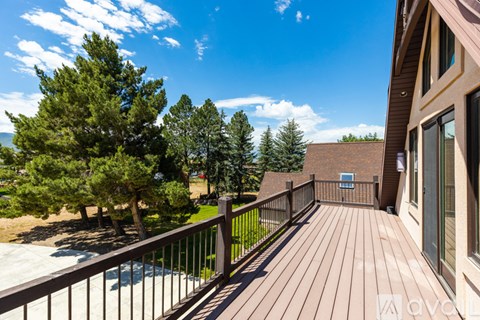 A deck with a railing and a hot tub surrounded by trees.