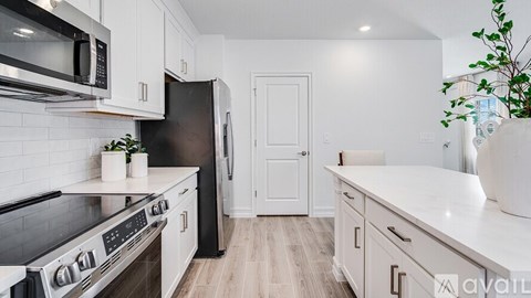 A kitchen with white cabinets and a black refrigerator.
