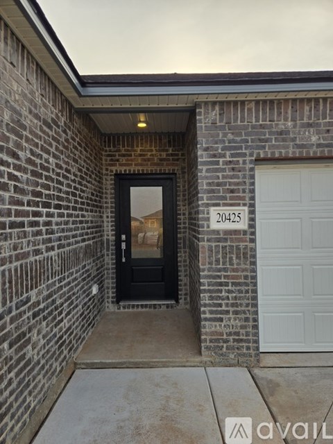 A black door is on the left side of a brick wall with a white garage door on the right.
