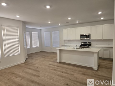 A spacious kitchen with white cabinets and a wooden floor.