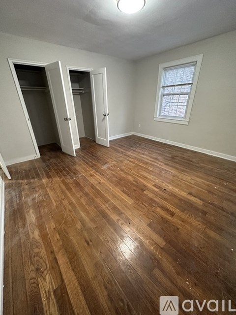 A room with wooden flooring and two open doors.