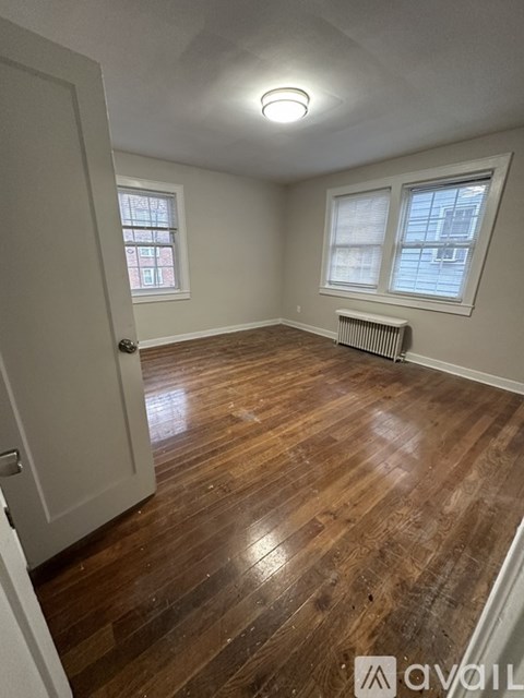 A room with wooden floors and a window with blinds.