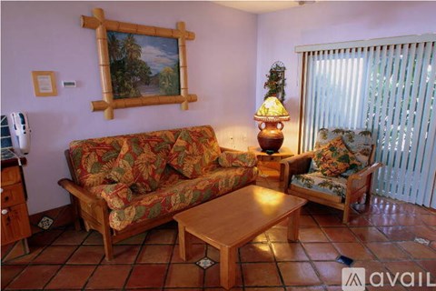 A living room with a couch, chair, and a painting on the wall.
