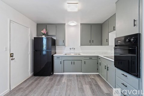 A kitchen with a black fridge and stove top oven.