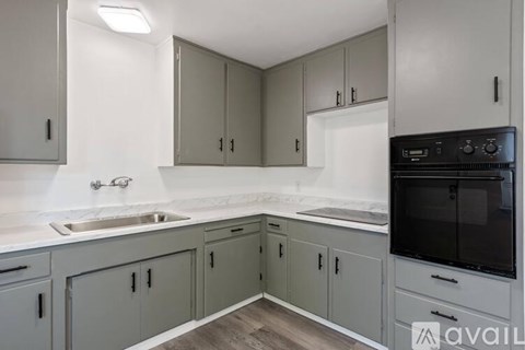 A kitchen with grey cabinets and a black oven.