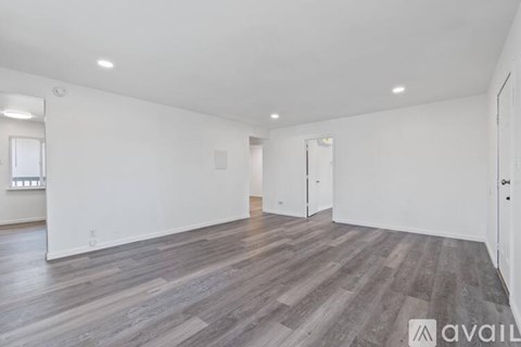 A spacious room with wooden flooring and white walls.