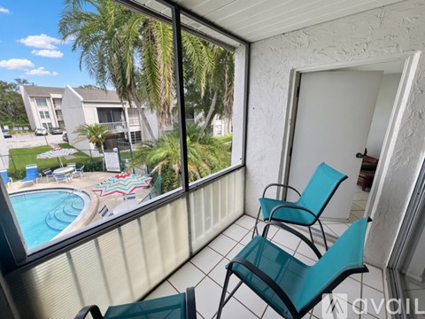 A balcony with two chairs and a view of a pool and houses.