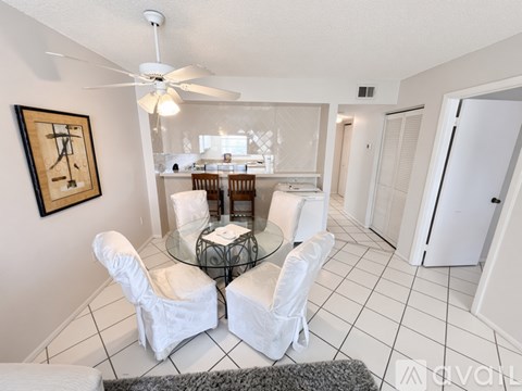 A living room with a glass table and white chairs.