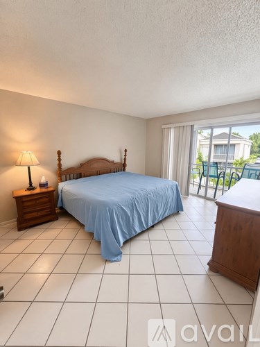 A bedroom with a bed, nightstand, and sliding glass doors.