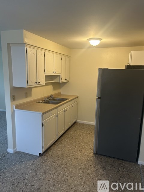 A kitchen with white cabinets and a black refrigerator.