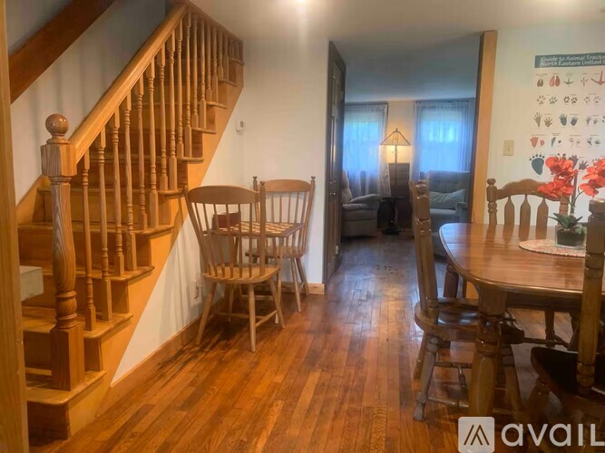 A living room with a wooden staircase and a dining table with chairs.
