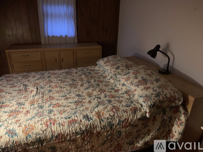 A bedroom with a floral bedspread and a window with curtains.