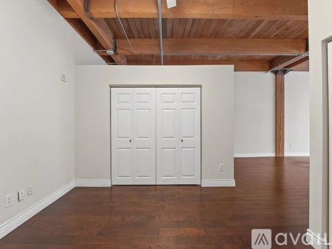 A room with a white door and wooden floor.