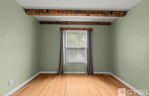 A room with wooden floors and a window with a curtain.