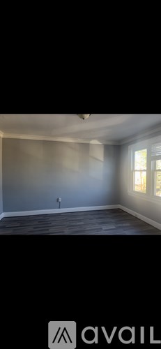 A room with a grey wall and wooden floor.