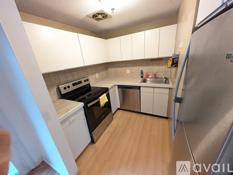 A kitchen with white cabinets and a stainless steel refrigerator.