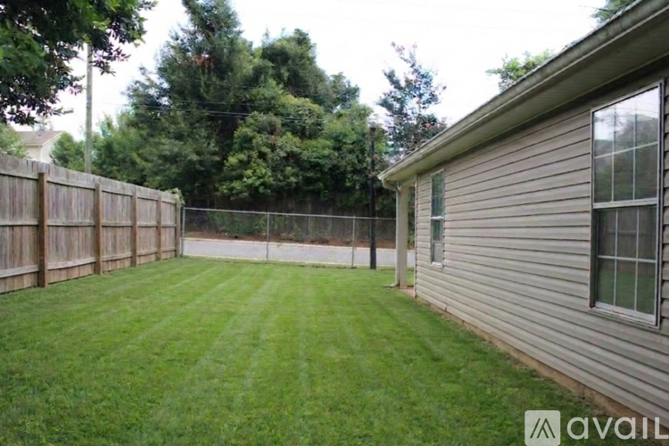 A backyard with a wooden fence and a house.