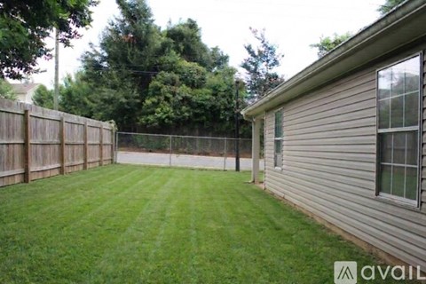 A backyard with a wooden fence and a house.