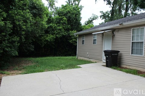A house with a driveway and a trash can in front.