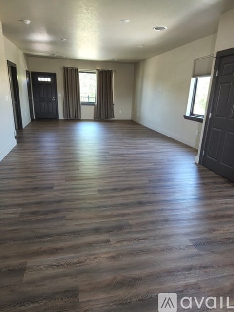 A room with wooden flooring and a window with curtains.