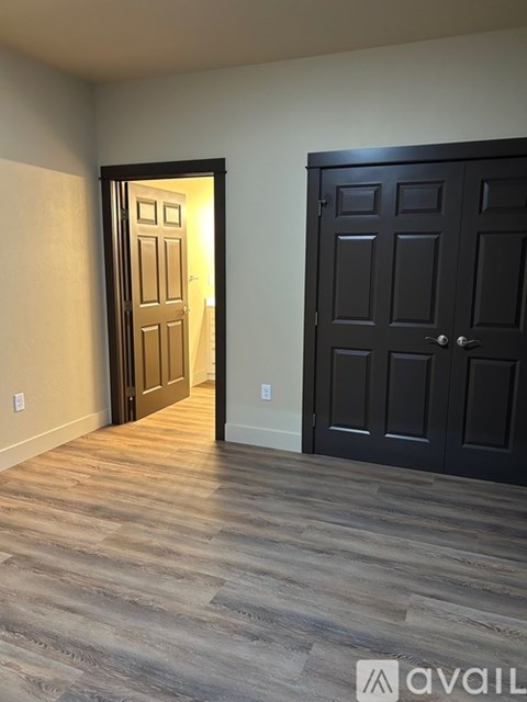 A room with a black door and a wooden floor.